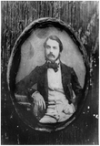 Thumbnail af portrait of a seated man, a table on the left