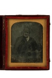 Thumbnail af A half length portrait of a sitting man.  His…