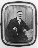 Esikatselunkuvan portrait of a seated man wearing glasses, wit… näyttö