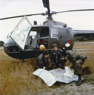 Twee vliegers en eeen legerluchtwaarnemer (KL) bij een Bo-105 in het veld.