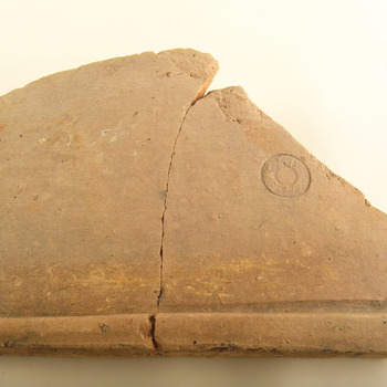 Gelijmd fragment van een daktegula van baksteen met stempel