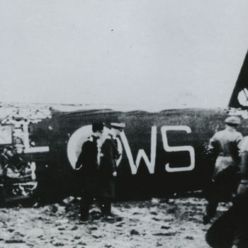 Foto van wrak Britse Vickers Wellington bommenwerper, codeletters WS, met Duitse militairen. Tekst: "Neergeschoten Engelse bommenwerper van het type Wellington 1C van het 9e Squadron, ergens in Holland. Let op uniform van Hollandse marechaussee".