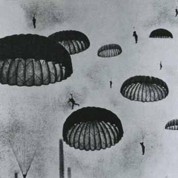 Foto van dalende Duitse parachutisten onder open parachutes.