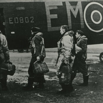Foto van bommenwerper bemanning die aan boord van Lancaster ED802 EM-M gaat. Tekst achterop: "Lancaster EM-M (207 Sqn) ED-802 Captain Sgt. J. McIntosh. Langar May 1943". Tekst er naast: "Bemanning van Lancaster EM-M van het 207 Sqdn. gaan aan boord. Capt. Sgt. J. McIntosh op de basis Langar mei 1943".