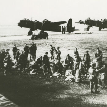 Foto Britse parachutisten. Op achtergrond Britse Short Stirling bommenwerpers (gezien de invasiestrepen fot uit juni 1944).