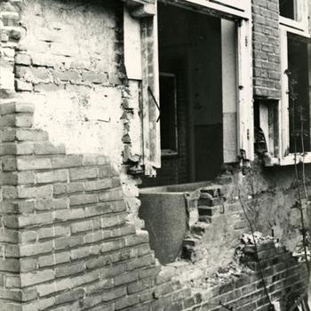 bakstenen muur met raam vernield door granaatinslag
