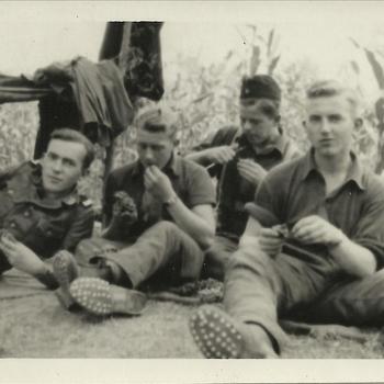 Vier jonge soldaten (Duits?) zitten buiten te eten