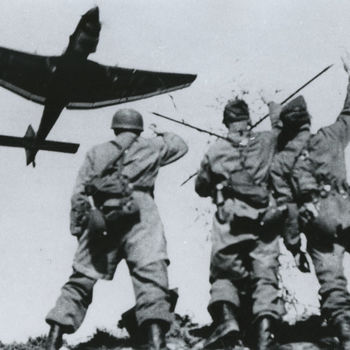 Foto van Duitse parachutisten die een laag overvliegende Stuka toewuiven. Tekst: "Duitse parachutisten begroeten een laagvliegende Ju-87 "Stuka"welken voor luchtsteun zorgden. Foto 11-5-'40 nabij Moerdijk"