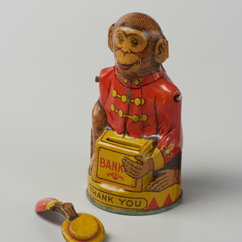 Spaarpot van blik in de vorm van een aap met een rode jas, 1947-1955